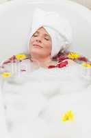 Relaxed woman taking a relaxing bath with a towel on her head