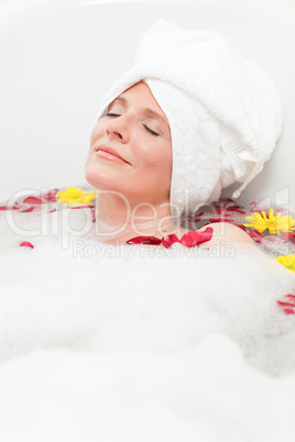 Relaxed woman taking a relaxing bath with a towel on her head