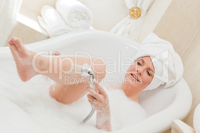 Smiling woman taking a bath with a towel on her head