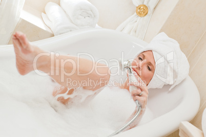 Smiling woman taking a bath with a towel on her head