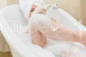 Smiling woman taking a bath with a towel on her head