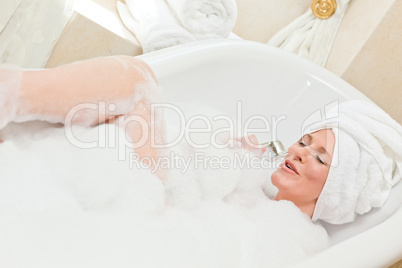 Charming woman taking a bath with a towel on her head