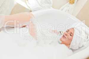 Charming woman taking a bath with a towel on her head