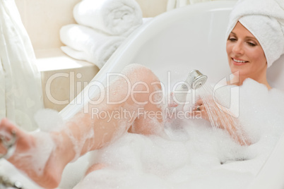 Smiling woman taking a bath with a towel on her head