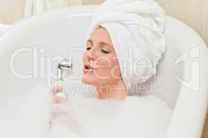 Charming woman taking a bath with a towel on her head