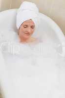Lovely woman taking a bath with a towel on her head