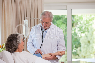 Senior doctor taking the blood pressure of his patient