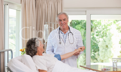 Senior doctor taking the blood pressure of his patient