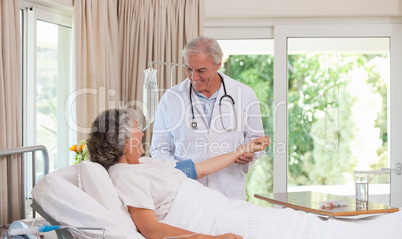 Senior doctor taking the blood pressure of his patient