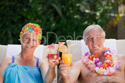 Mature couple drinking a cocktail  beside the swimming pool