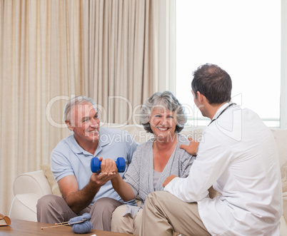 Handsome doctor helping his patient to do exercises