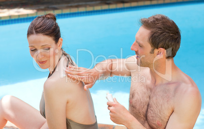 Man putting sun cream on the back of his wife