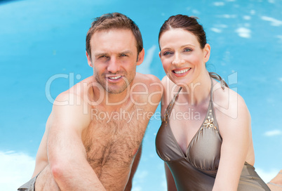 Couple looking at the camera beside the swimming pool