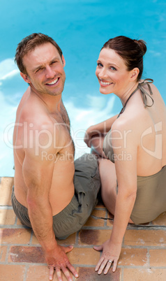 Couple looking at the camera beside the swimming pool