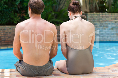 Couple sitting beside the swimming pool