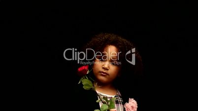 Young black girl/child with curly hair holding a red rose against black background 1