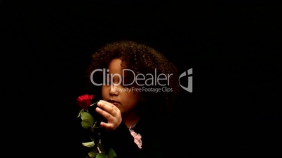 Young black girl/child with curly hair holding a red rose against black background 2
