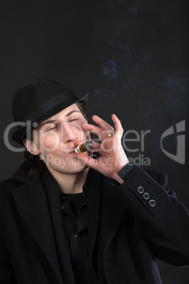 Man in black cloth and hat smoke cigar
