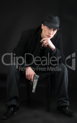 Man with pistol sit in black cloth
