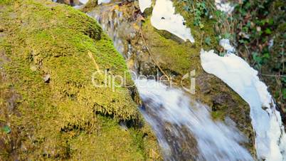 Waterfall and mossy rock in winter