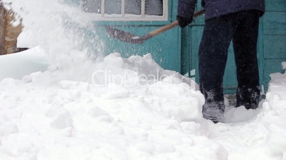 Man clearing snow off with shovel against house