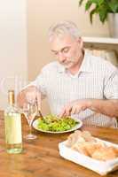 Senior mature man eat vegetable salad and white wine