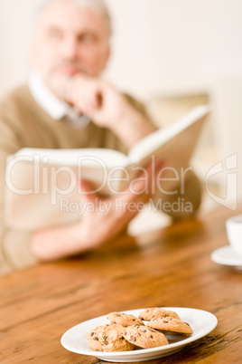 Senior mature man, cookies at wooden table