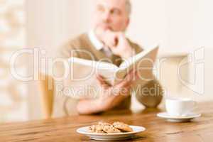 Senior mature man, cookies at wooden table
