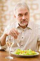 Senior mature man eat healthy salad and white wine