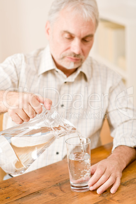 Senior mature man pour water sitting at table