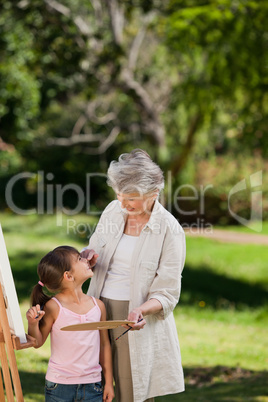 Grandmother and her granddaughter painting in the garden