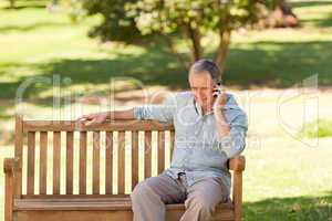 Retired man phoning in the park