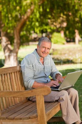 Elderly man working on his laptop in the park