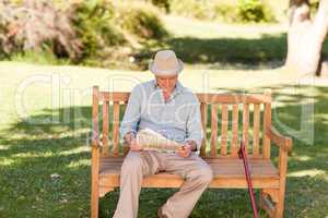 Retired man reading his newspaper on the bench