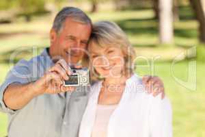 Elderly couple taking a photo of themselves in the park