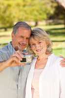 Elderly couple taking a photo of themselves in the park