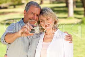 Elderly couple taking a photo of themselves in the park