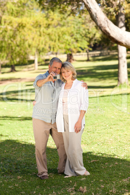 Elderly couple taking a photo of themselves in the park