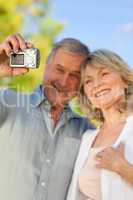 Smiling couple taking a photo of themselves in the park