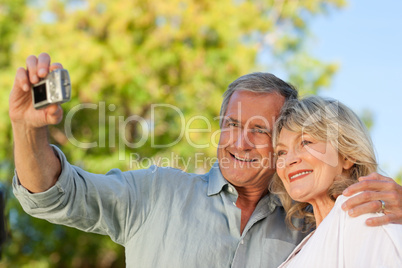 Smiling couple taking a photo of themselves in the park