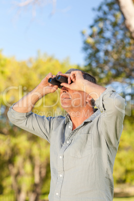 Senior man looking at the sky with his binoculars