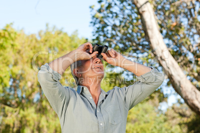 Senior man looking at the sky with his binoculars