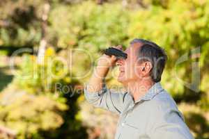 Elderly man looking at the sky with his binoculars