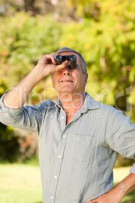 Elderly man looking at the sky with his binoculars