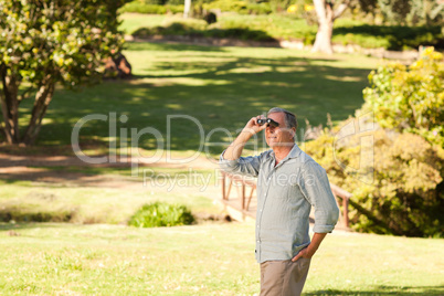 Elderly man looking at the sky with his binoculars