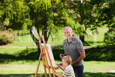 Grandfather and his grandson painting in the garden