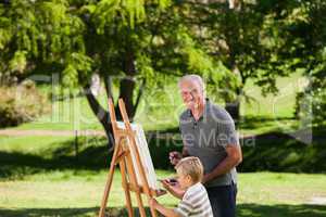Grandfather and his grandson painting in the garden