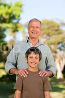 Grandfather with his grandson looking at the camera in the park