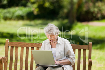 Mature woman working on her laptop on the bench