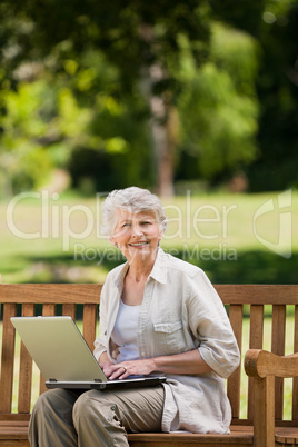 Mature woman working on her laptop on the bench